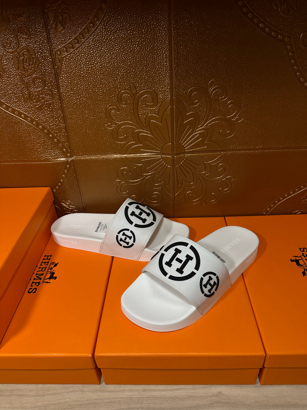 White slide sandals with black logo strap, centered front view