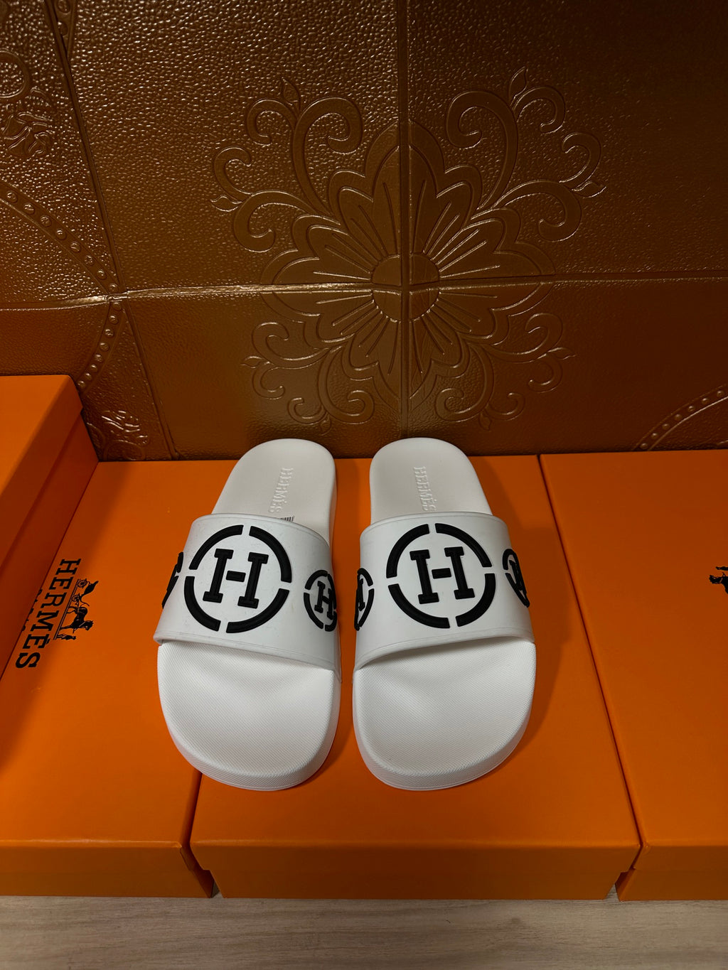 White slide sandals with black interlocking logo strap
