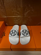 White slide sandals with black interlocking logo strap