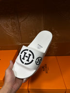 White slide sandals with black logo strap, close heel view