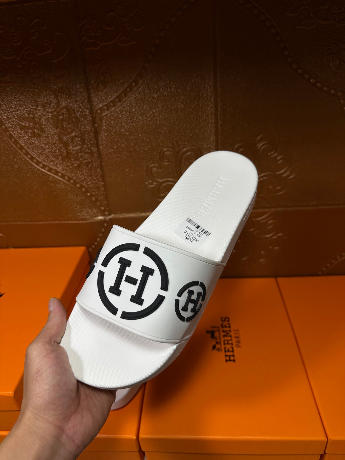 White slide sandals with black logo strap, close heel view