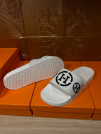 White slide sandals with textured outsole and black logo strap