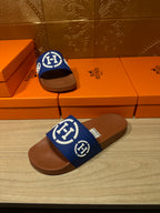 Blue logo slide sandals with brown footbeds, one upright on shoeboxes