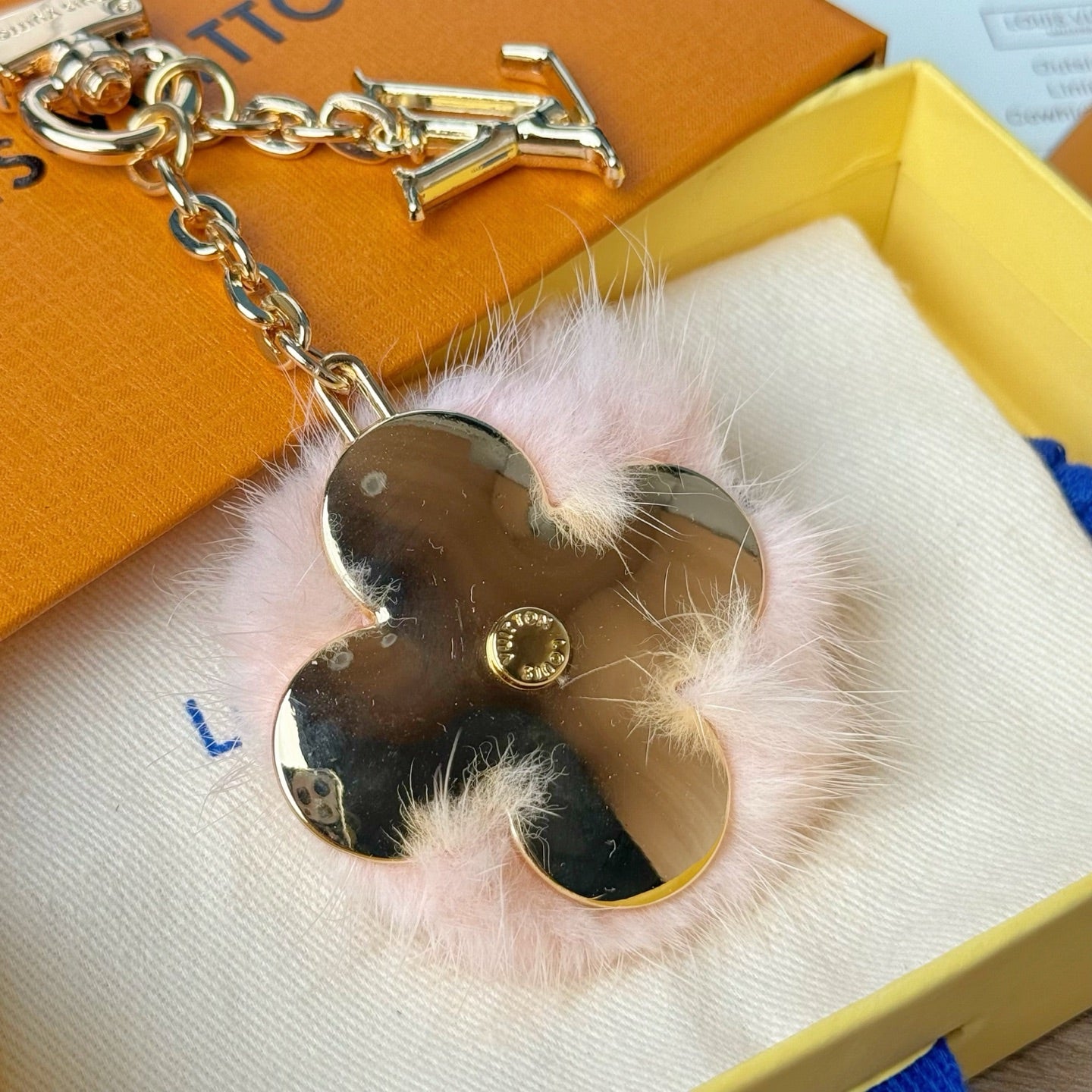 Louis Vuitton keychain detail: gold chain with heart mirror charm and pink fur