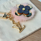 Louis Vuitton keychain close-up with blue flower charm, gold emblem, and pink fur