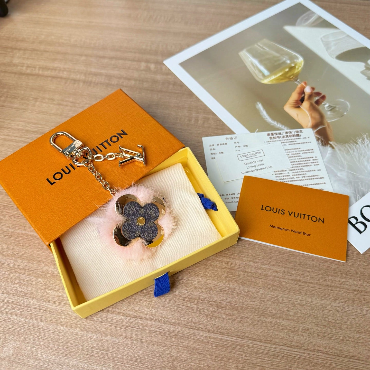 Louis Vuitton keychain in box with gold chain and blue flower charm with pink fur