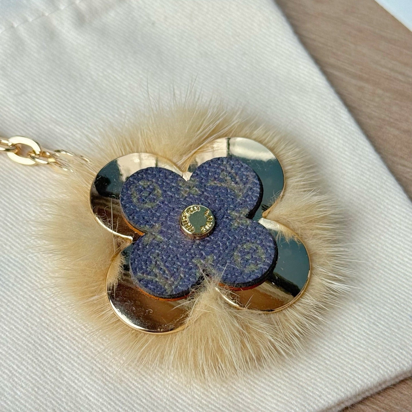 Louis Vuitton blue flower keychain detail with faux fur trim and gold center emblem