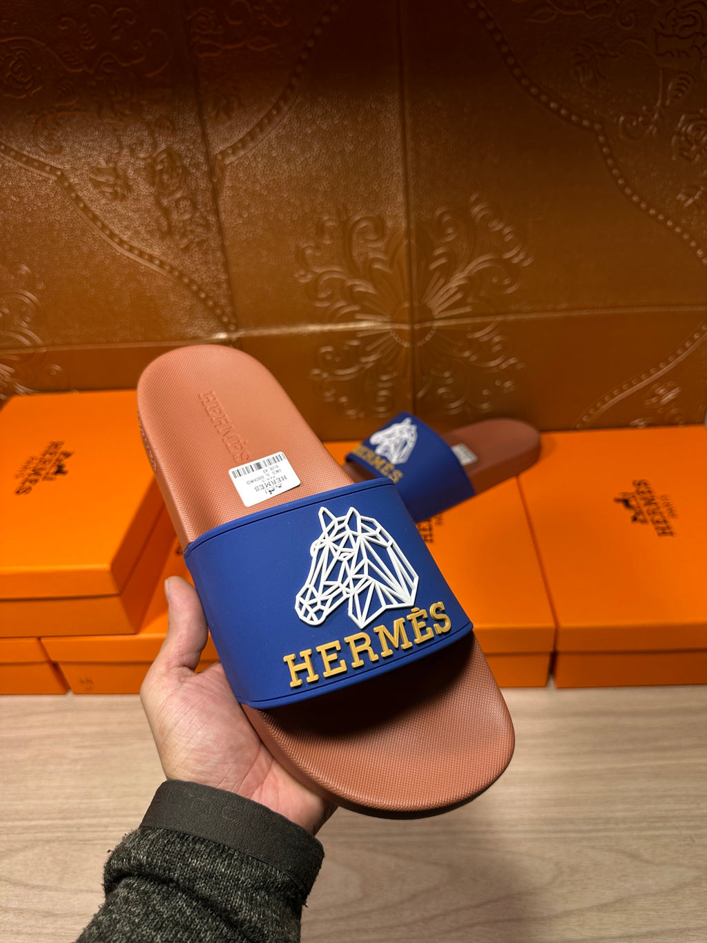 Handheld Hermes slide sandal with blue logo strap and tan-brown footbed