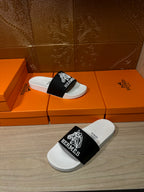 Hermes slide sandals on boxes, white sole with black strap and white Hermes logo