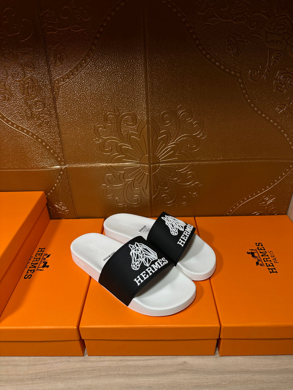 Hermes slide sandals on orange boxes, white footbed and black strap with white Hermes lettering