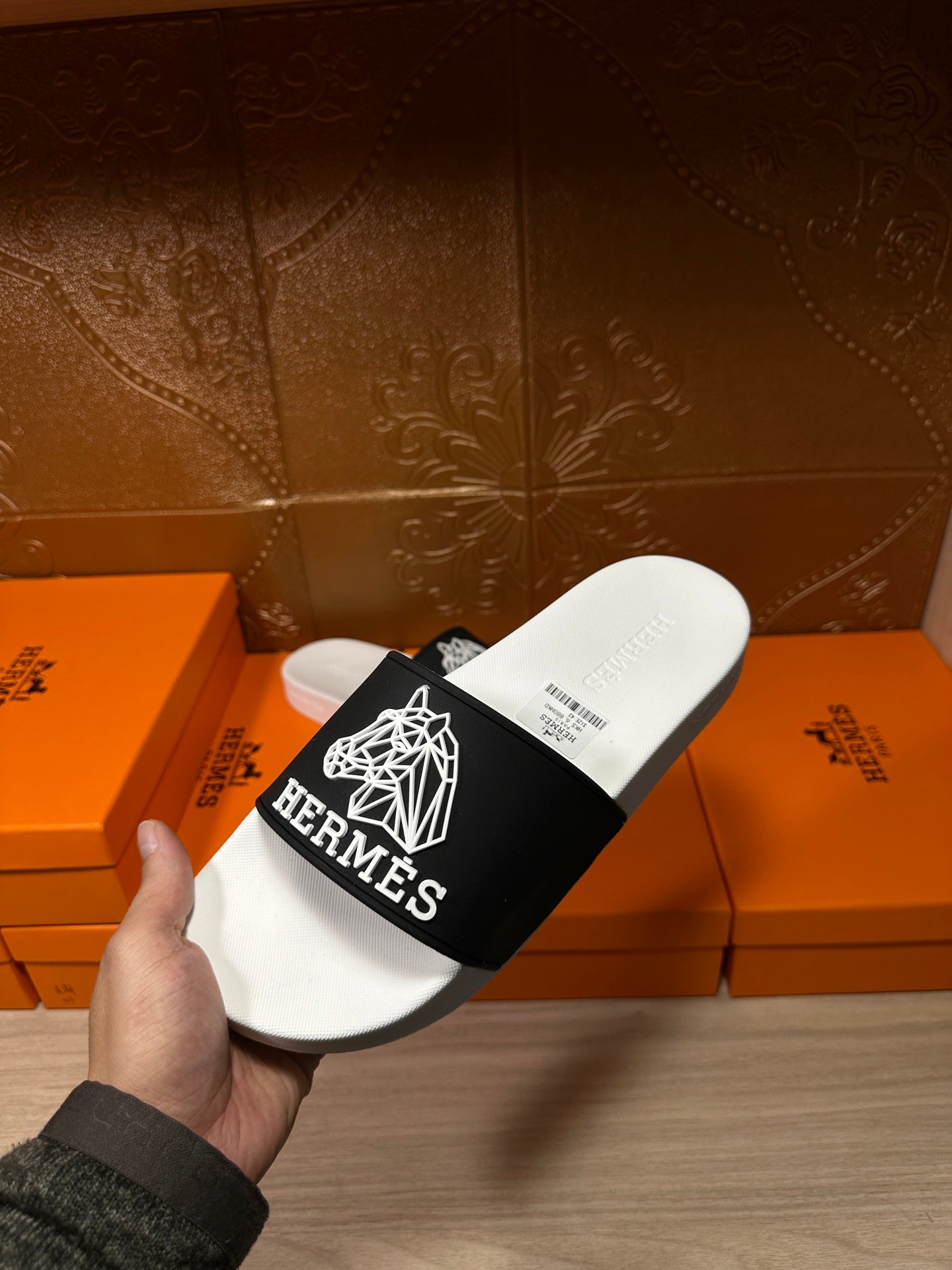 Hermes slide sandal in hand, white sole and black strap with white Hermes logo detail