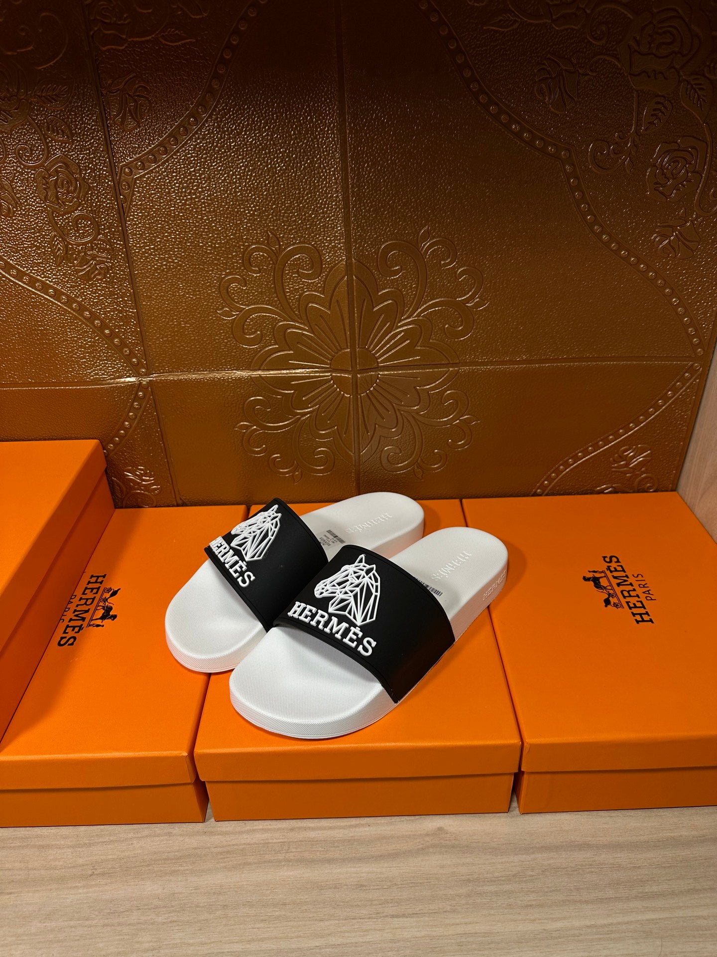 Hermes slide sandals, angled view with white sole and black wide strap with Hermes emblem