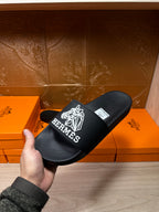 Hermes black slide sandal with white geometric logo and Hermes branding on strap