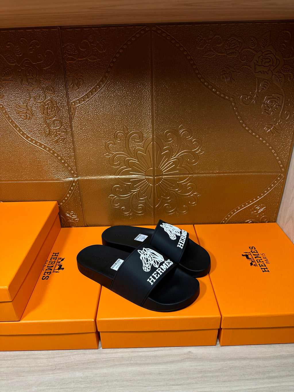 Hermes black slide sandals with white Hermes logo graphic on the strap