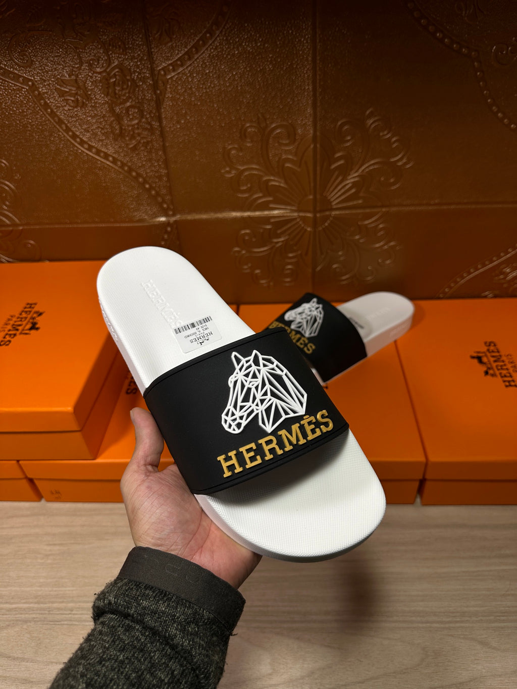 Hermes slide sandal held in hand, white footbed with black logo strap