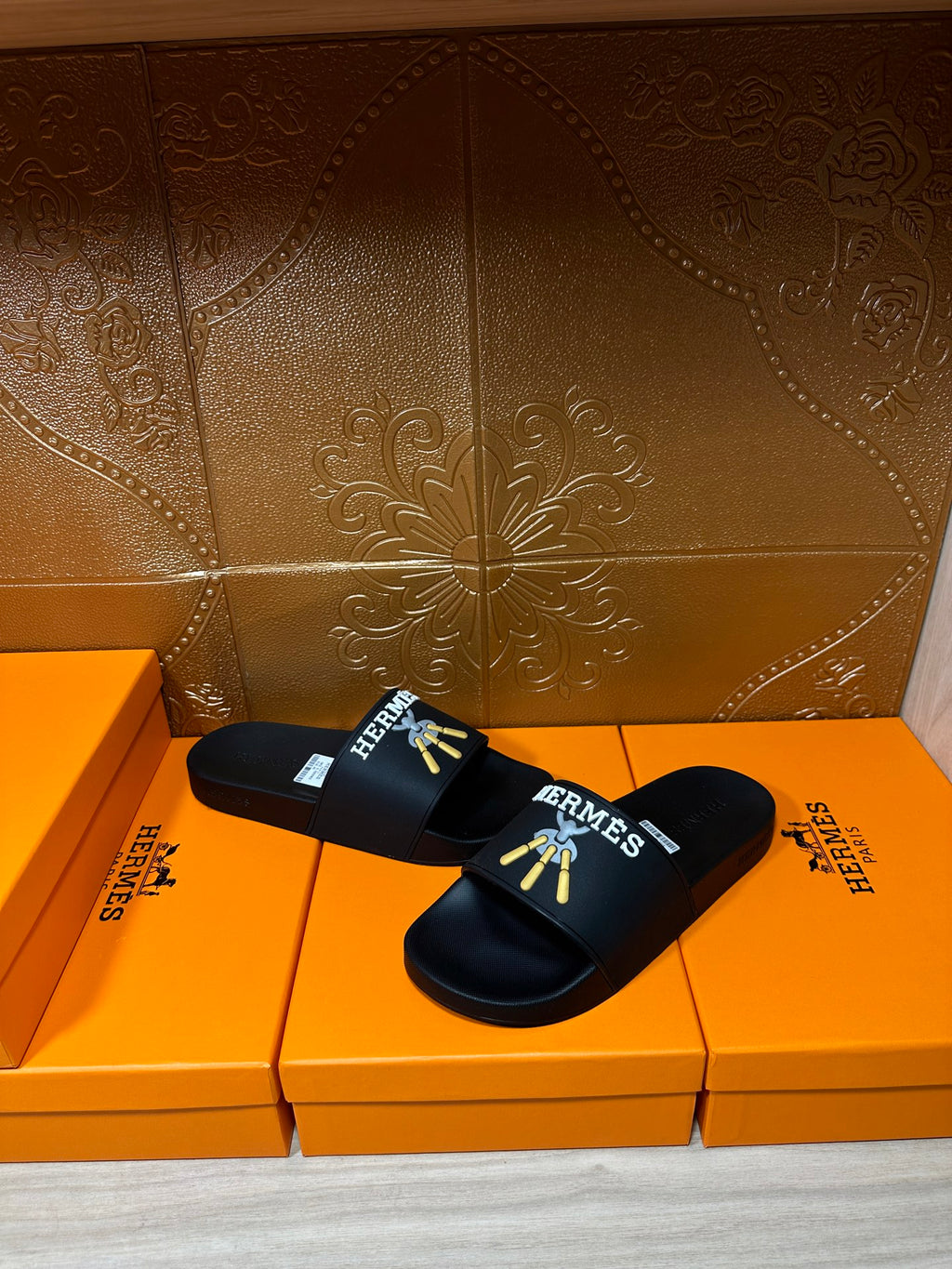 Hermes black slide sandals with gold graphic artwork on upper