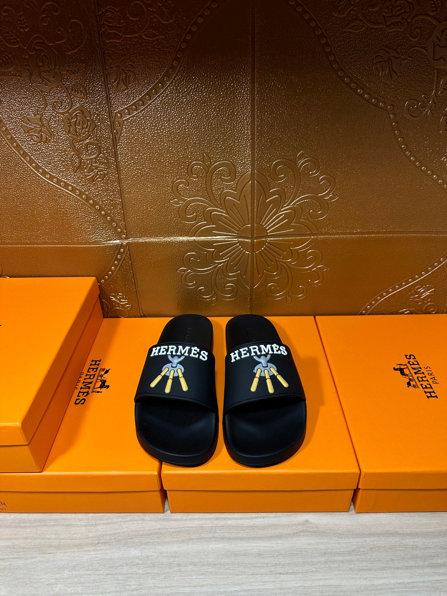 Hermes black slide sandals with gold graphic logo on strap