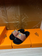 Hermes sandals, mauve cross strap over dark footbed with gold Hermes logo and motif.