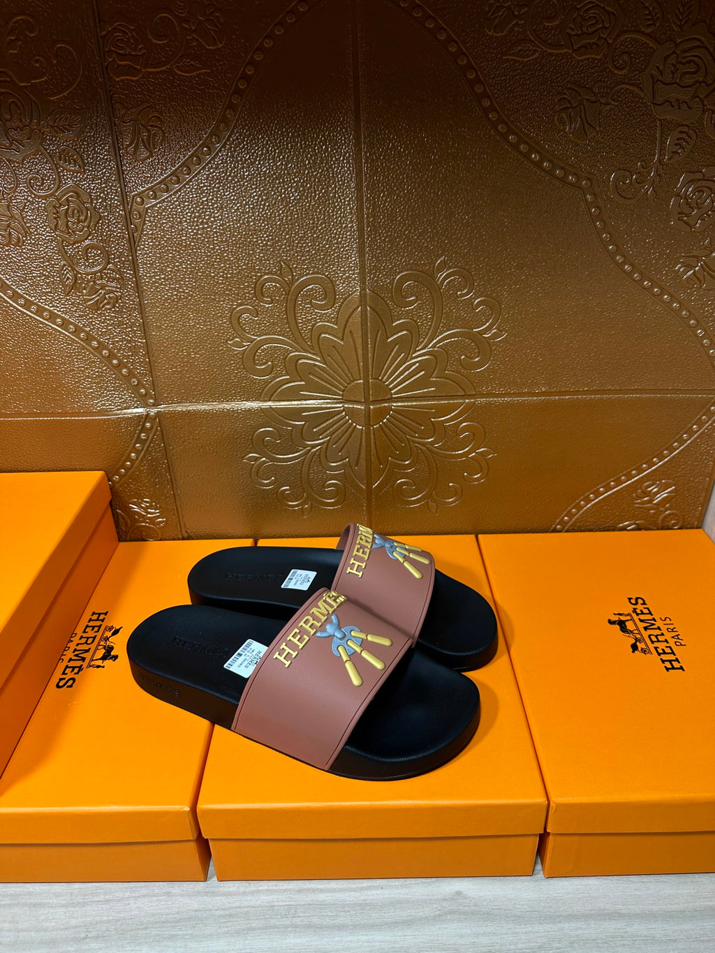 Hermes slide sandal pair, mauve strap and dark sole with Hermes logo and colorful design.