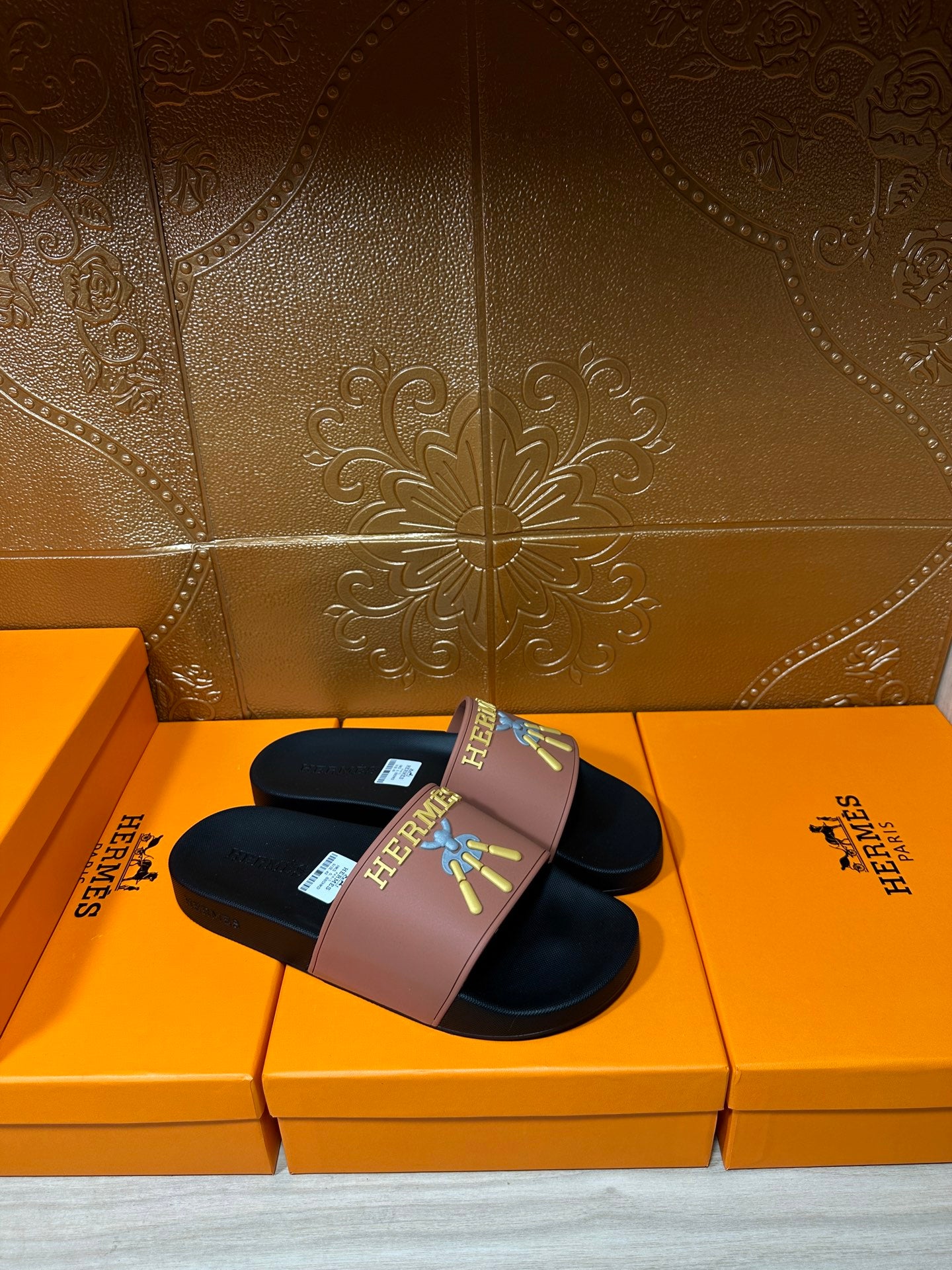 Hermes slide sandal pair, mauve strap and dark sole with Hermes logo and colorful design.