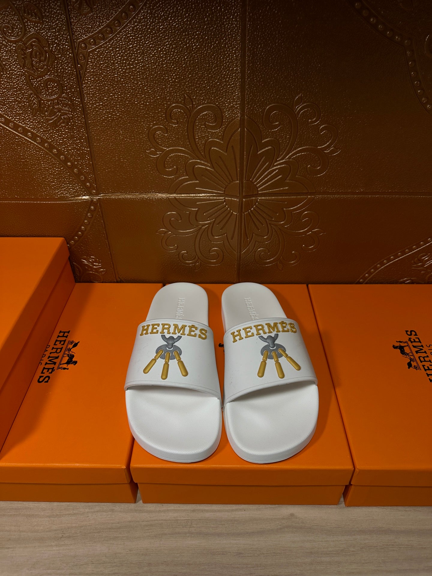 White Hermes slide sandals with single strap and gold logo on top