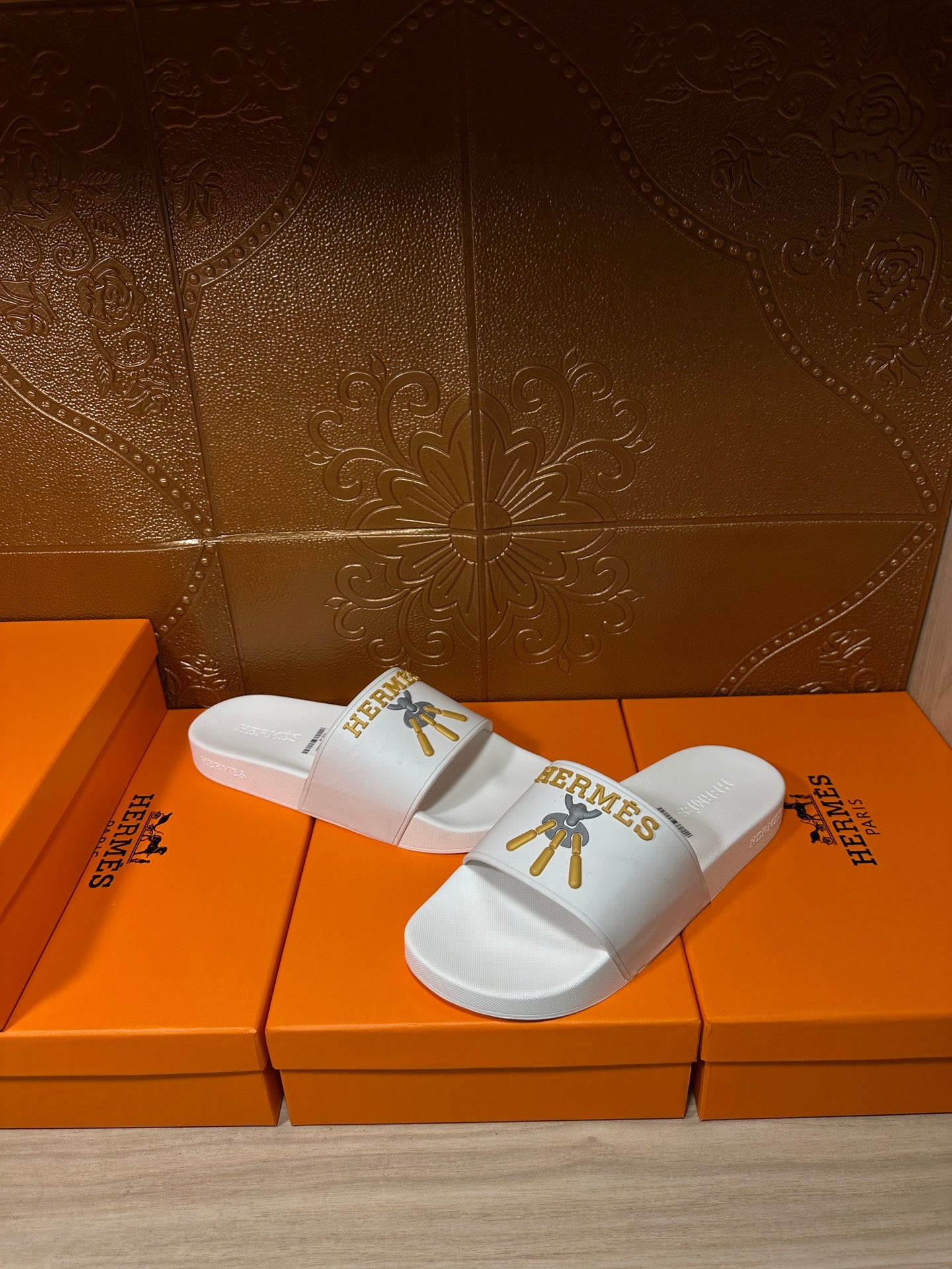White Hermes slide sandals with gold emblem on strap, side view