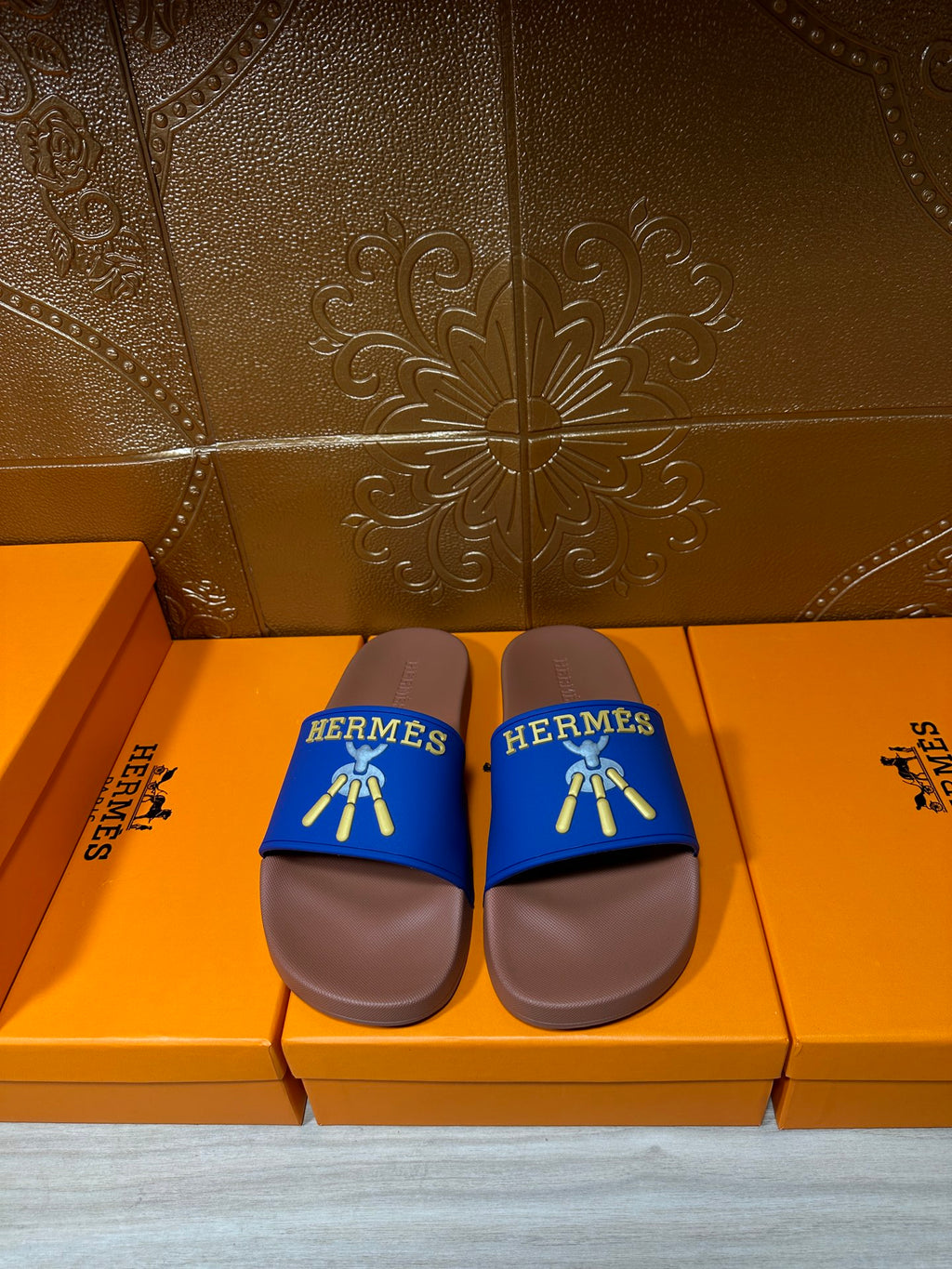Hermès slide sandals with blue straps and tan sole, gold logo detail on top