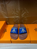 Hermès slide sandals with blue straps and tan sole, gold logo detail on top