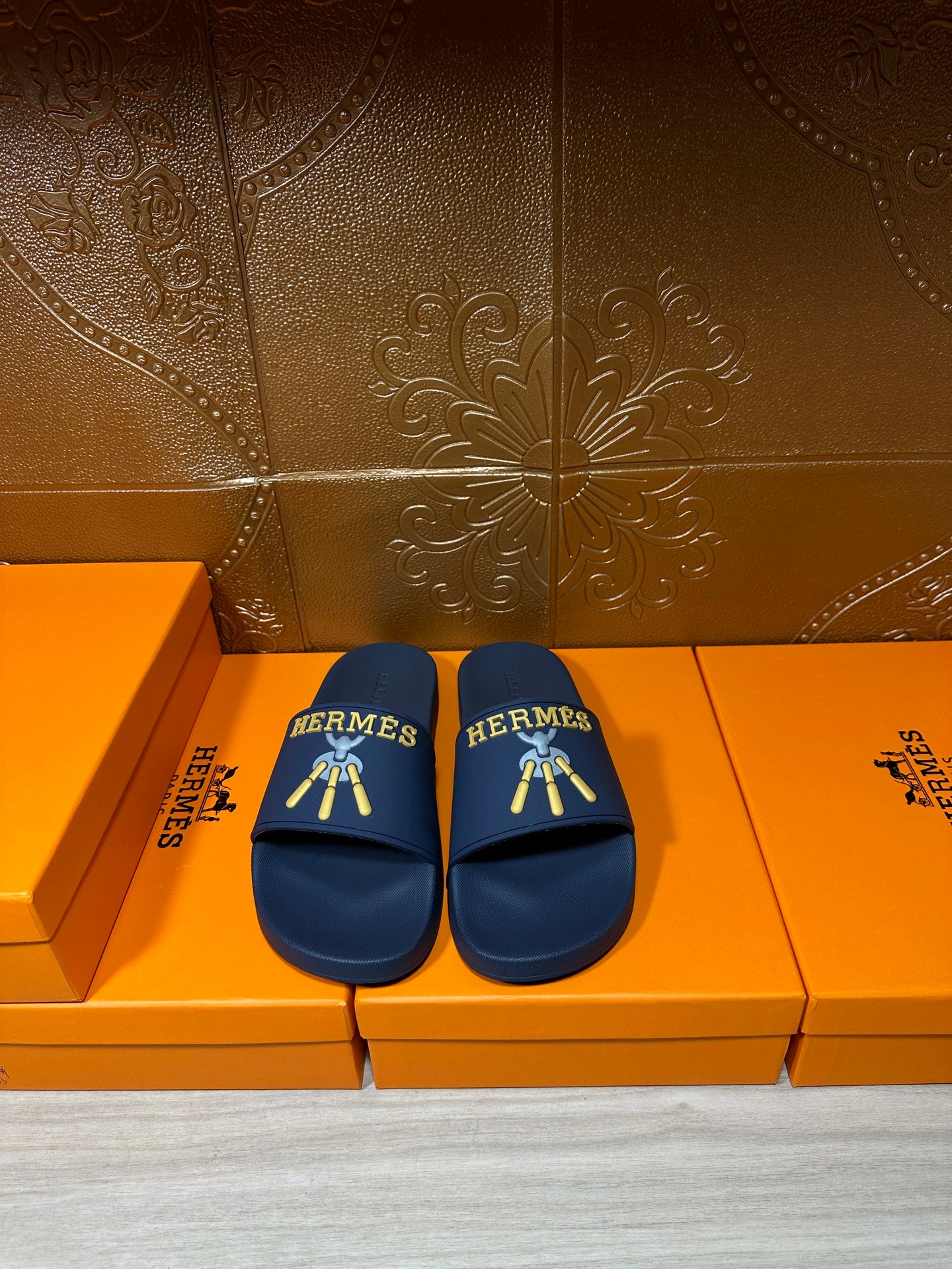 Hermes blue slide sandals with gold HERMES logo and striped charm graphic
