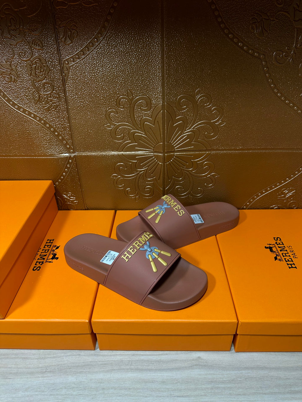 Hermes taupe slide sandals, diagonal view, multicolor logo patch on wide strap