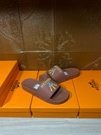 Hermes taupe slide sandals, diagonal view, multicolor logo patch on wide strap