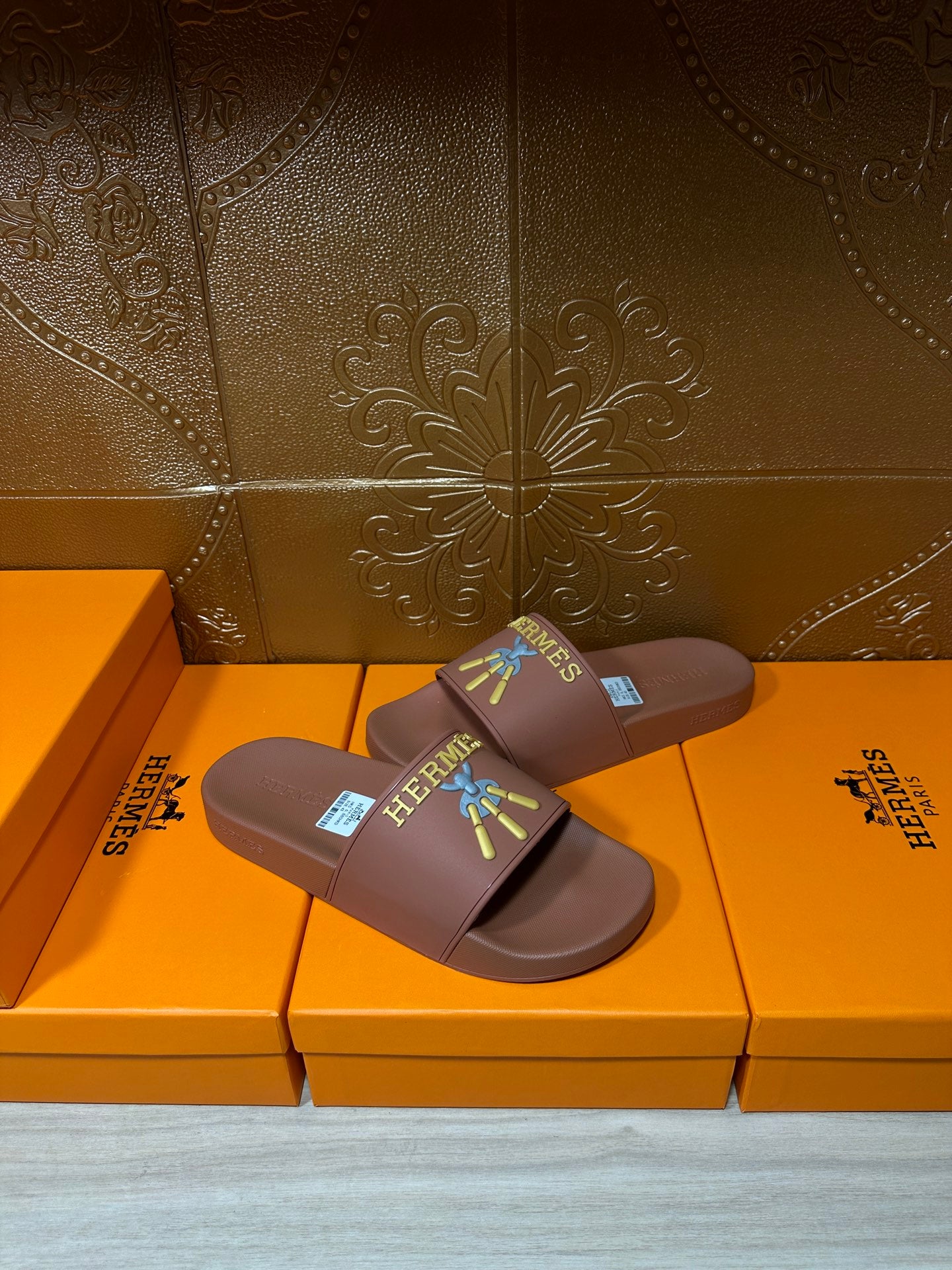 Hermes taupe slide sandals, diagonal view, multicolor logo patch on wide strap