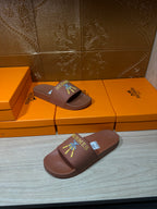 Hermes taupe slide sandals, one pair in foreground with multicolor logo patch