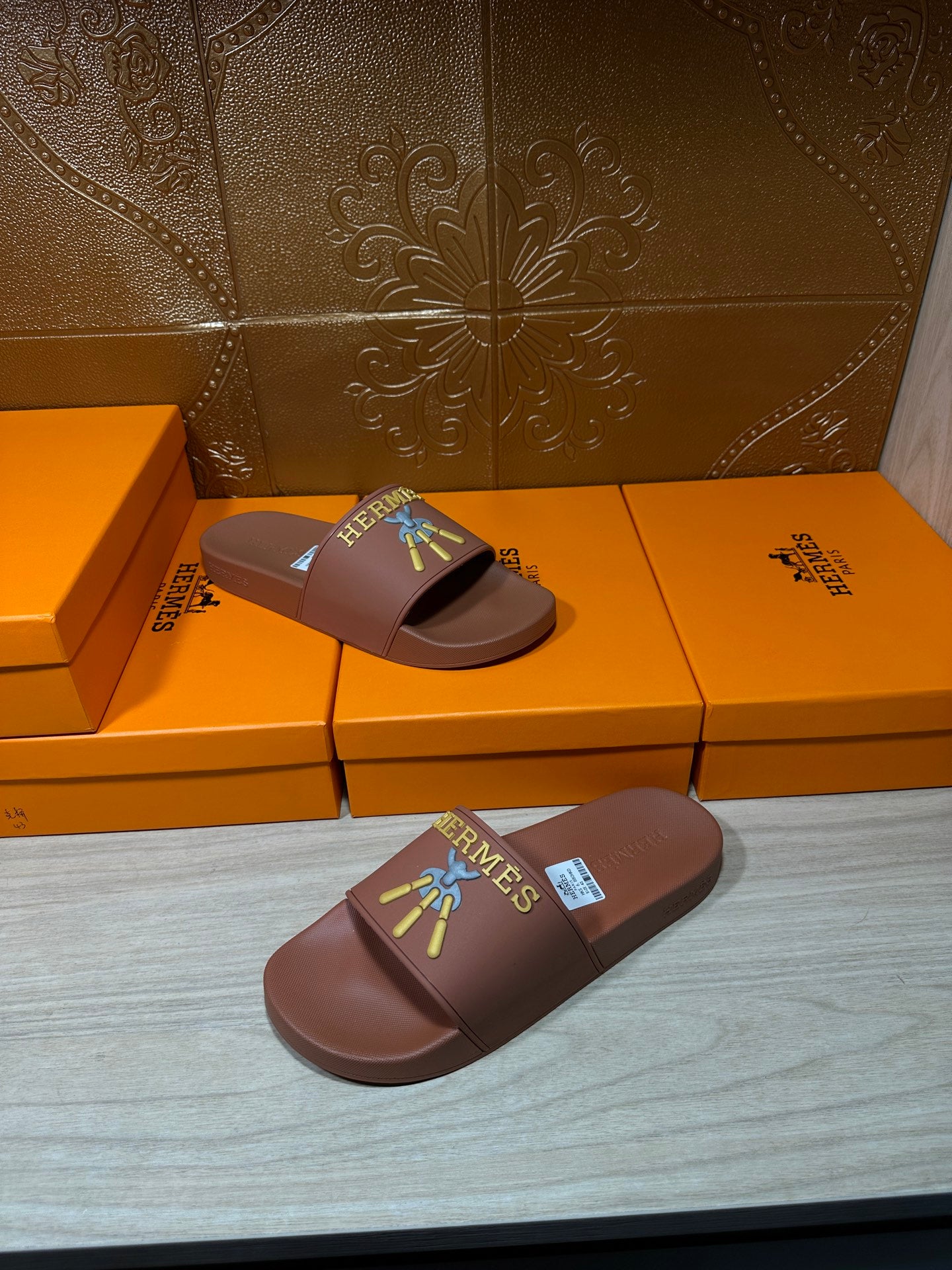 Hermes taupe slide sandals, one pair in foreground with multicolor logo patch