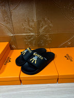 Hermes slide sandals, black slip-on slides with logo graphic on the front strap.