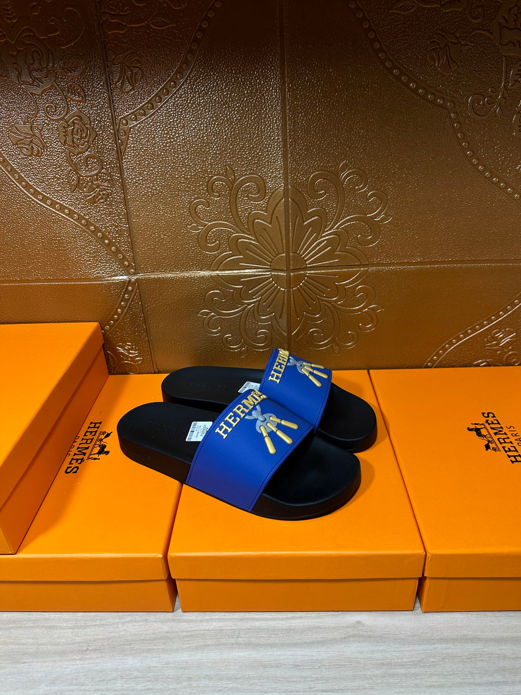 Hermes slide sandals with blue upper featuring gold emblem on black footbeds