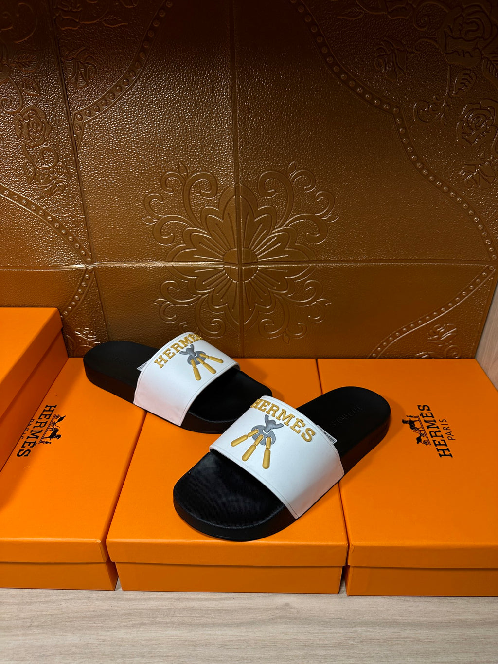 Hermes slide sandal held in hand, white strap with gold Hermes emblem