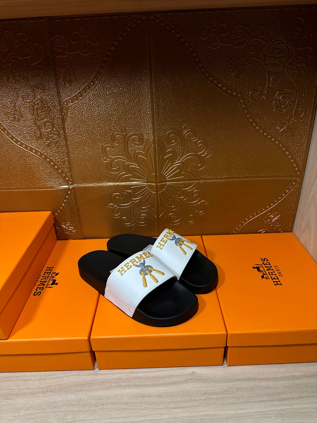 Hermes slide sandals with white strap and gold emblem over black footbed