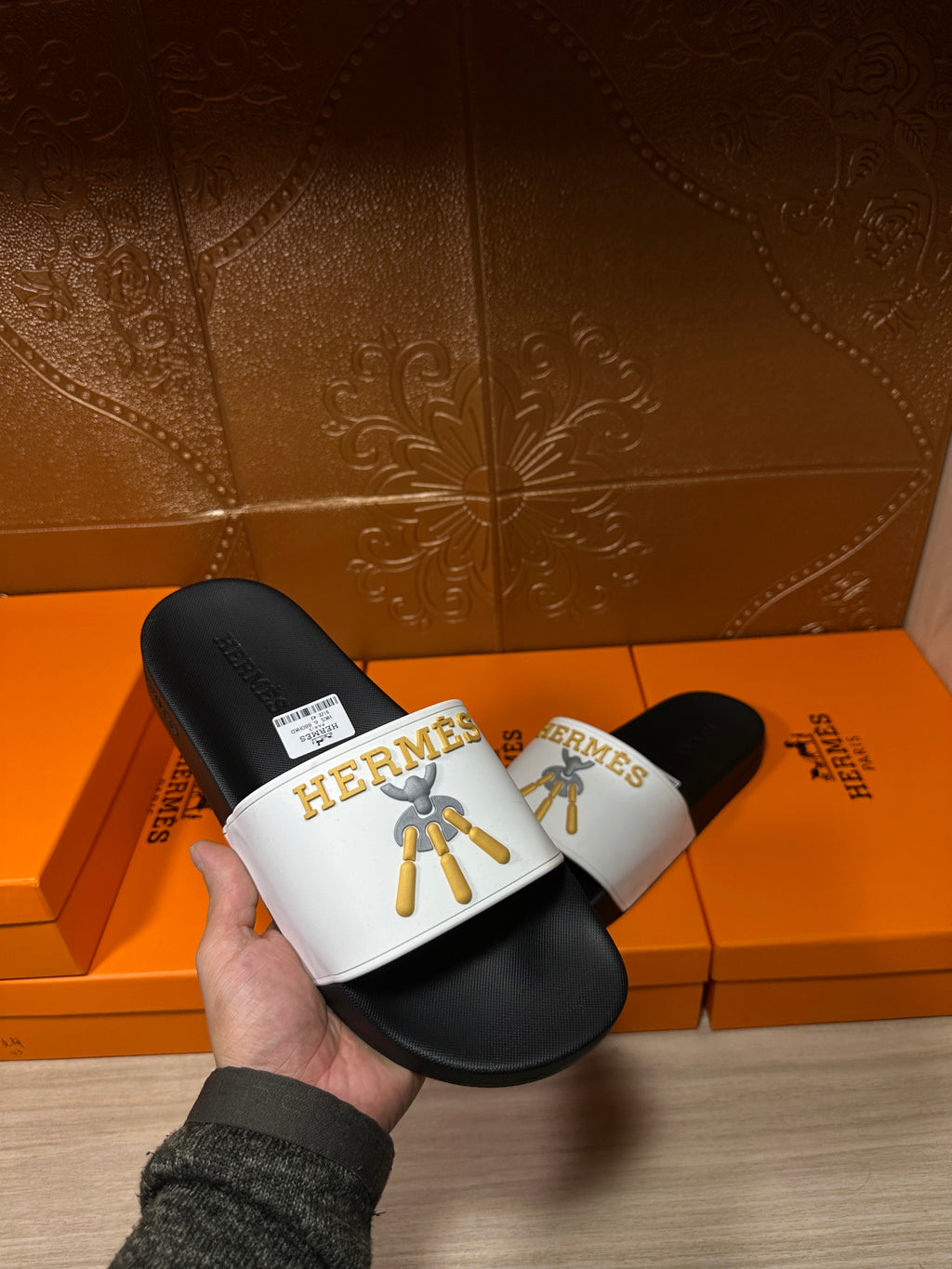 Hermes slide sandal held in hand, black footbed with white logo strap