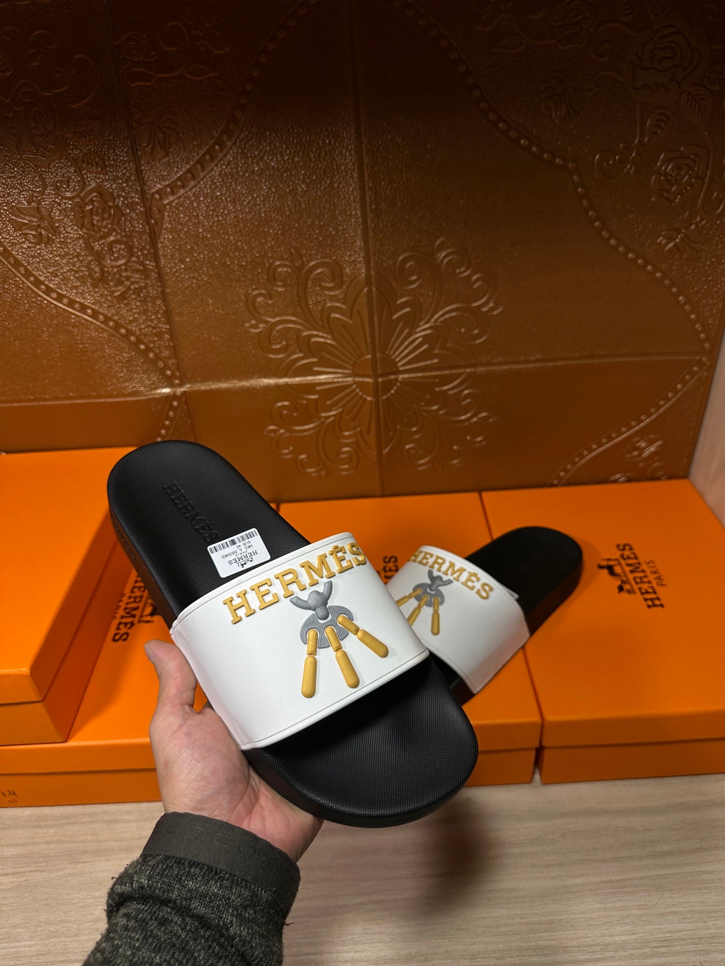 Hermes slide sandal held in hand, black footbed with white logo strap