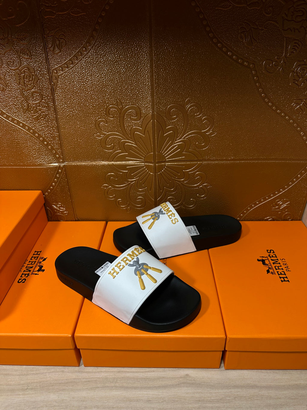 Hermes slide sandals with white logo band and gold emblem, black sole