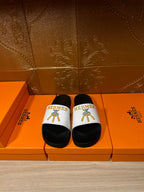Hermes slide sandals with black footbed and white logo strap with gold emblem