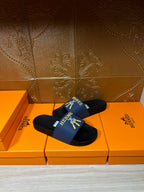 Hermes slide sandals with blue logo strap and cushioned black footbed