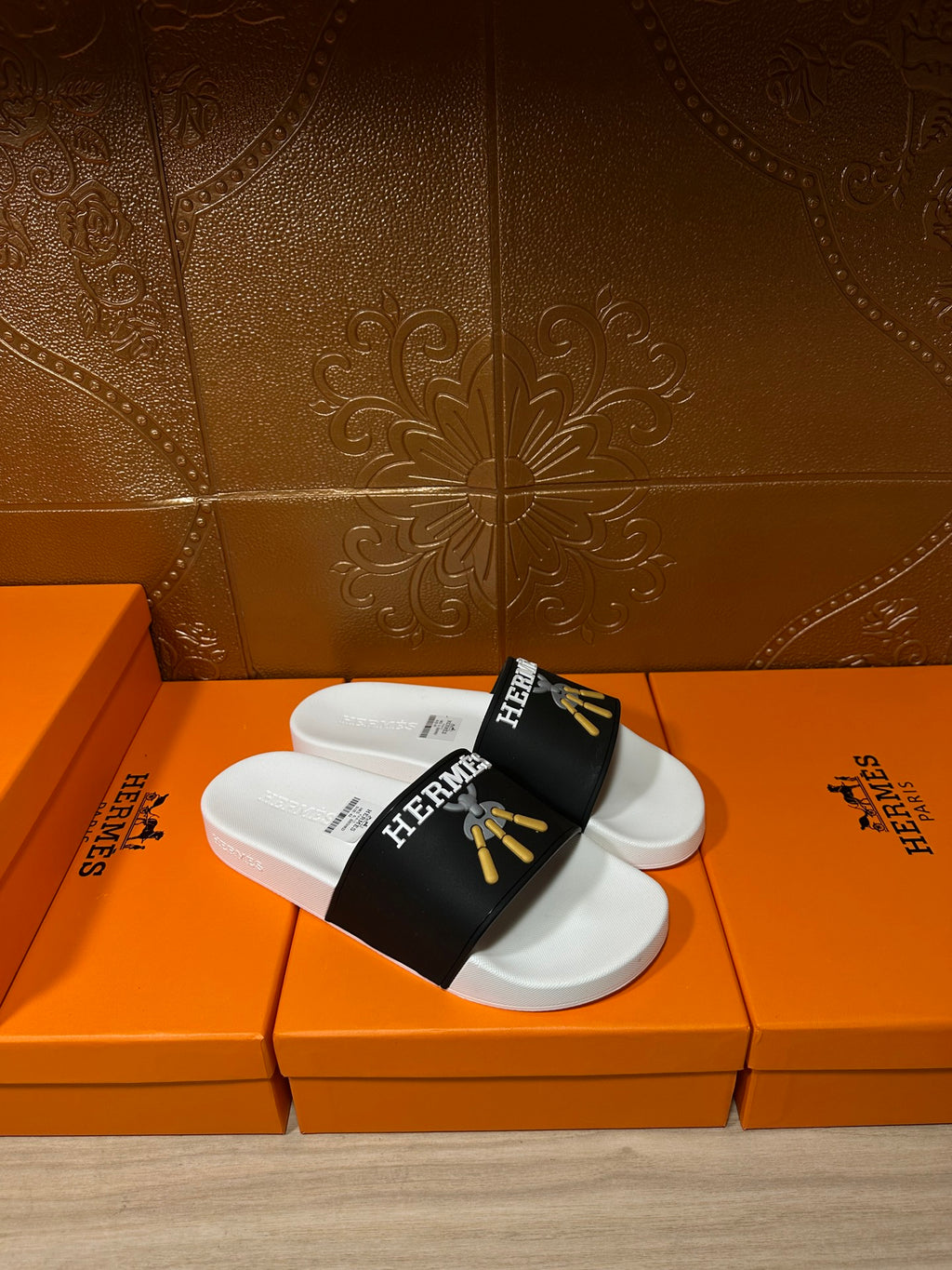 Pair of white slide sandals with black Hermes strap and gold tassel emblem