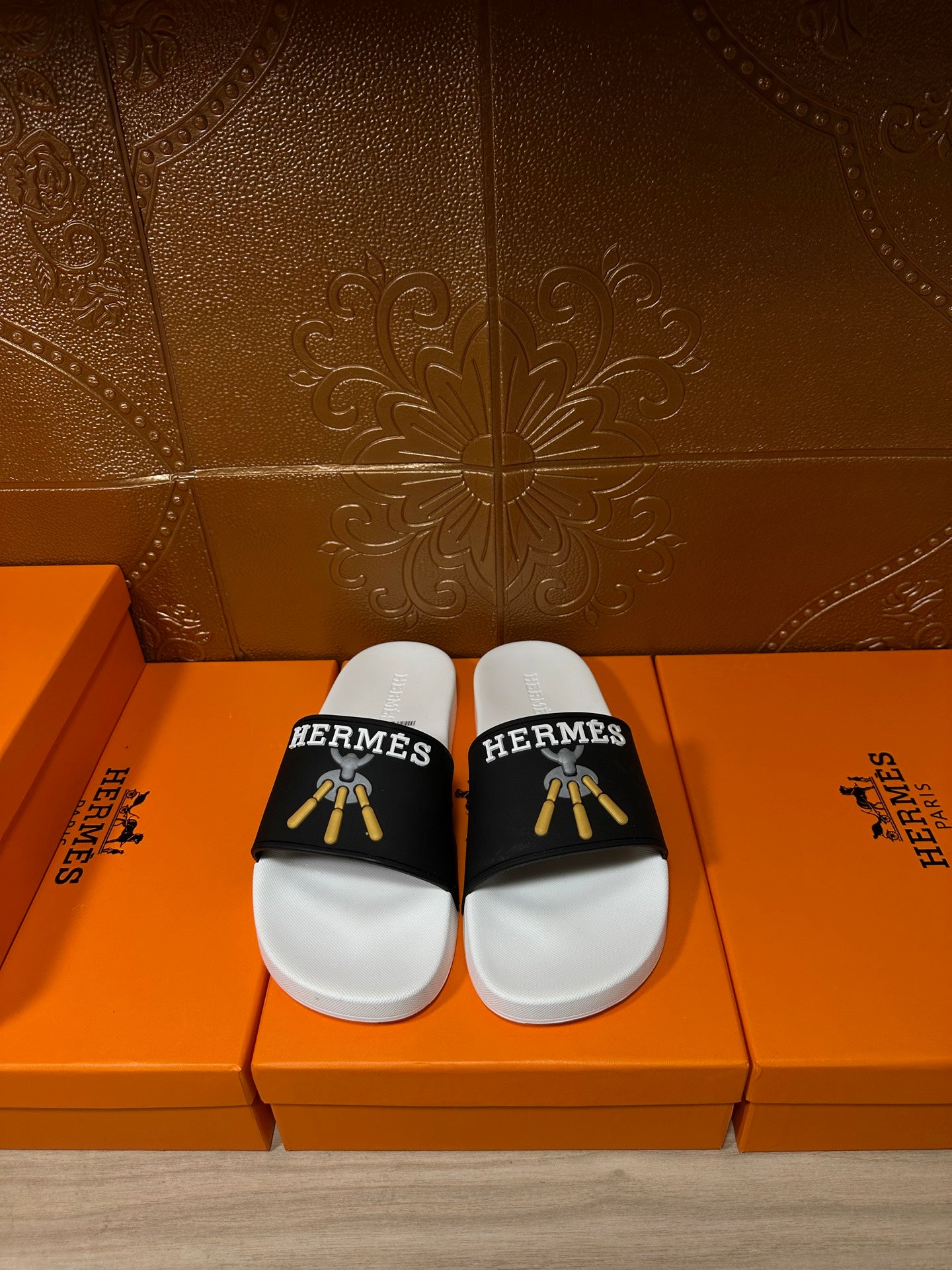 White slide sandals with black Hermes strap and gold tassel detail