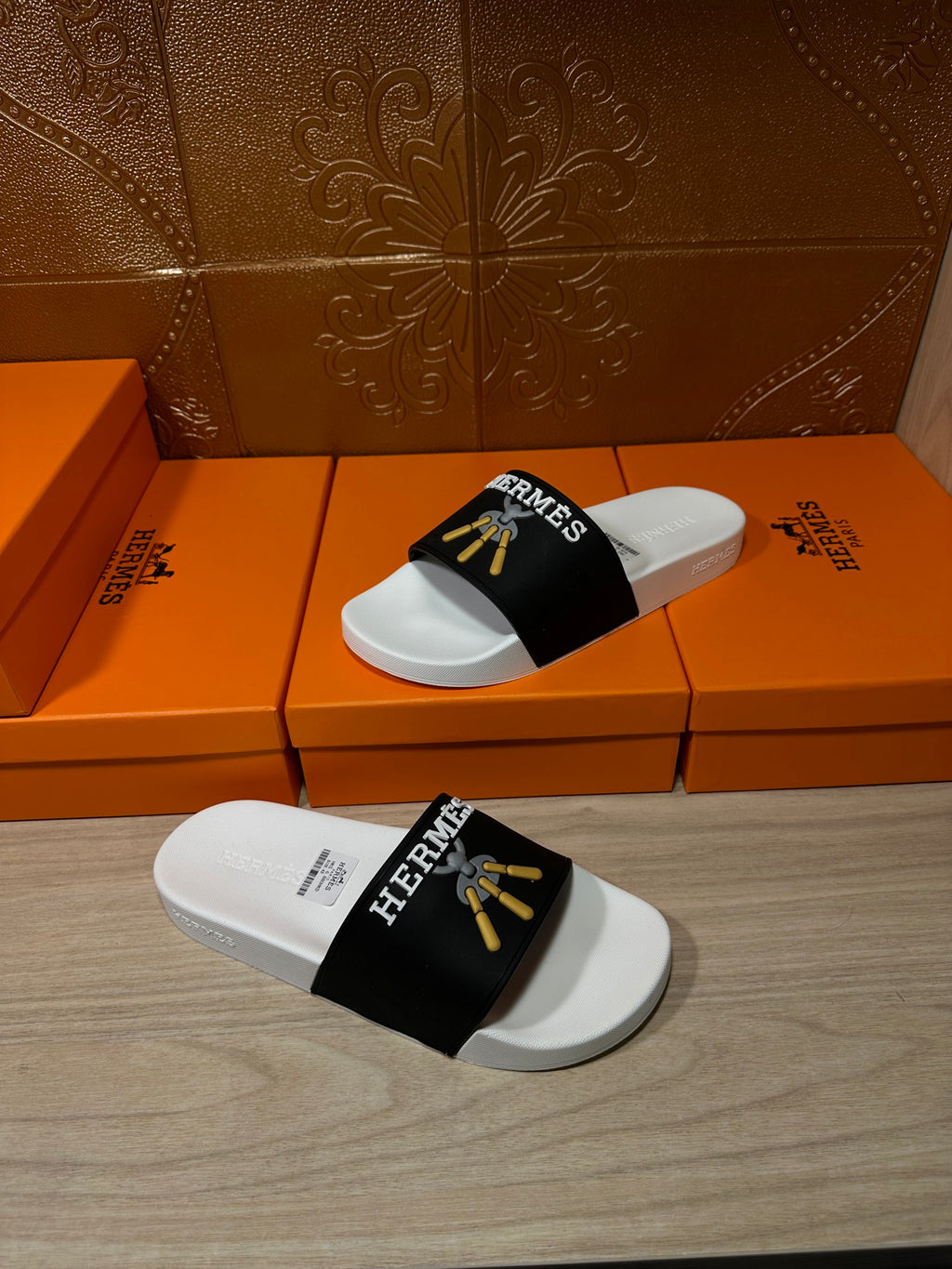White slide sandal with black Hermes strap and gold tassel motif