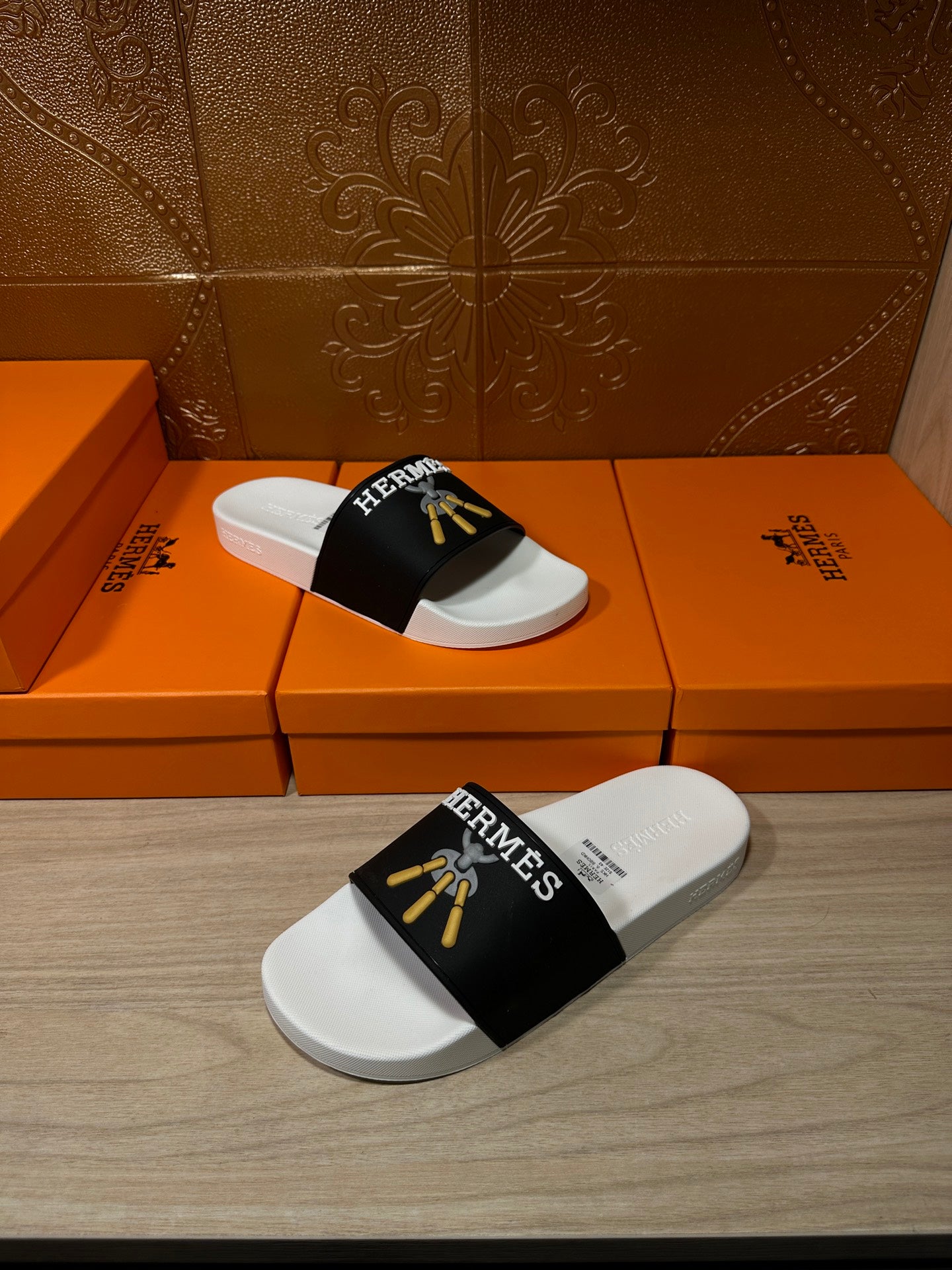 White slide sandals with black Hermes strap and gold tassel detail, side view
