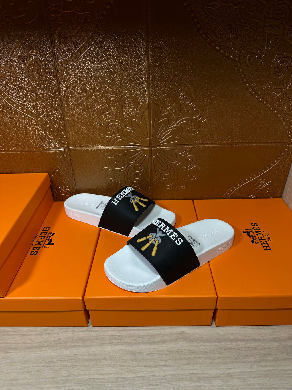 White slide sandals with black Hermes strap and gold tassel motif