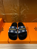 Black slide sandals with navy strap and white H pattern
