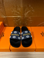 Black slide sandals with navy strap and white H pattern